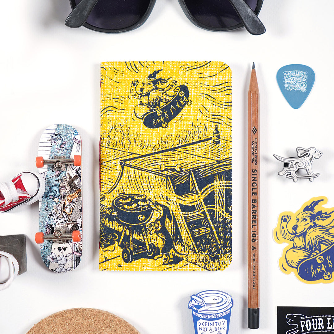 go skate day inspired pocket notebook with a cover featuring a dog skateboarding over a halfpipe and another dog grabbing a hot dog off a charcoal grill