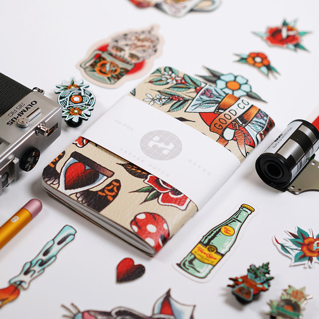 layflat knolling of pocket notebook, topo chico, hp5 film, tattoos, stickers, and an olympus 45rc