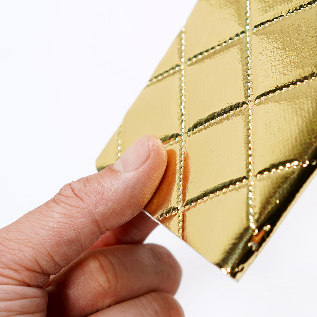 holding a shiny cushiony pocket notebook in gold