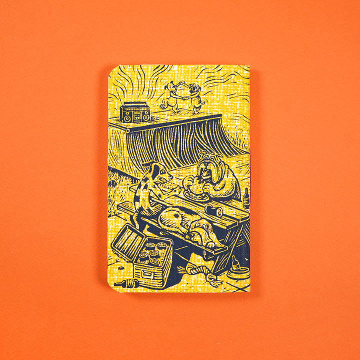 pocket notebook cover featuring two dogs dancing next to a stereo, two other dogs sitting on a picnic table eating, another dog sleep on the table's bench right next to an open beer cooler