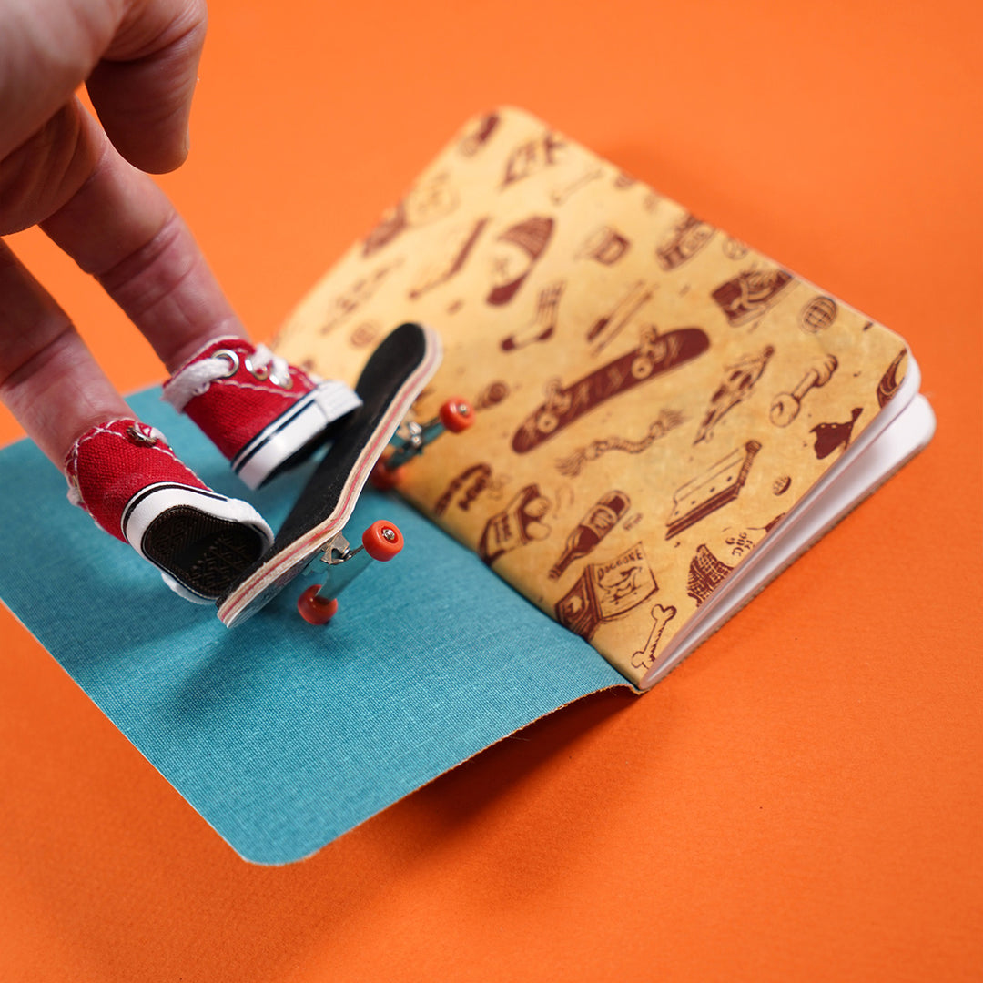 finger skating with tiny red converse shoes inside a dapper notes notebook