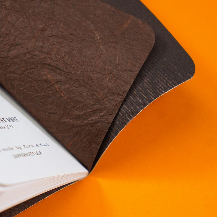 closeup of the pocket notebook insides with a brown endsheet cover, a wrinkled decorative endsheet that is also brown but slightly lighter toned