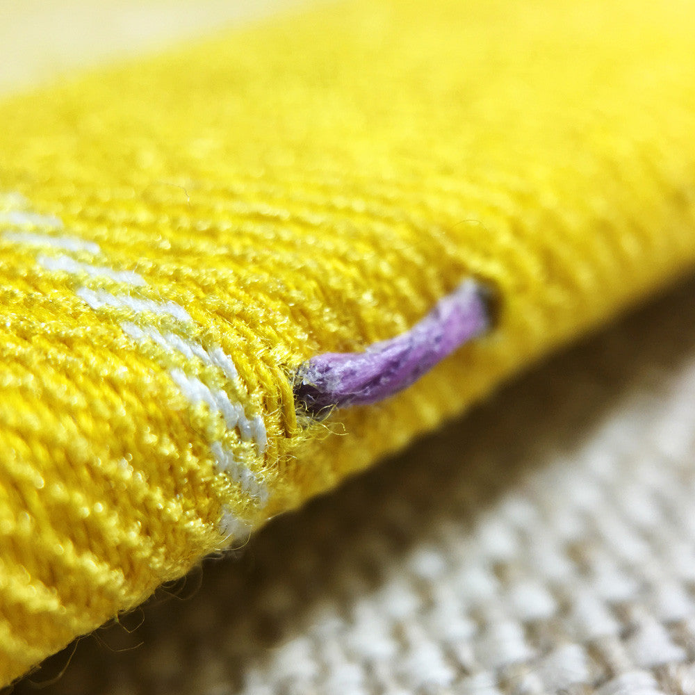 purple thread sewn into yellow notebook